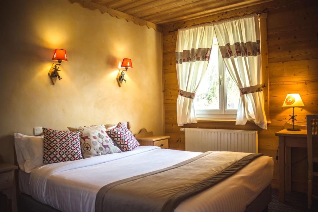 1 dormitorio con 1 cama con 2 lámparas y una ventana en Le Relais Du Mont Blanc, en Magland