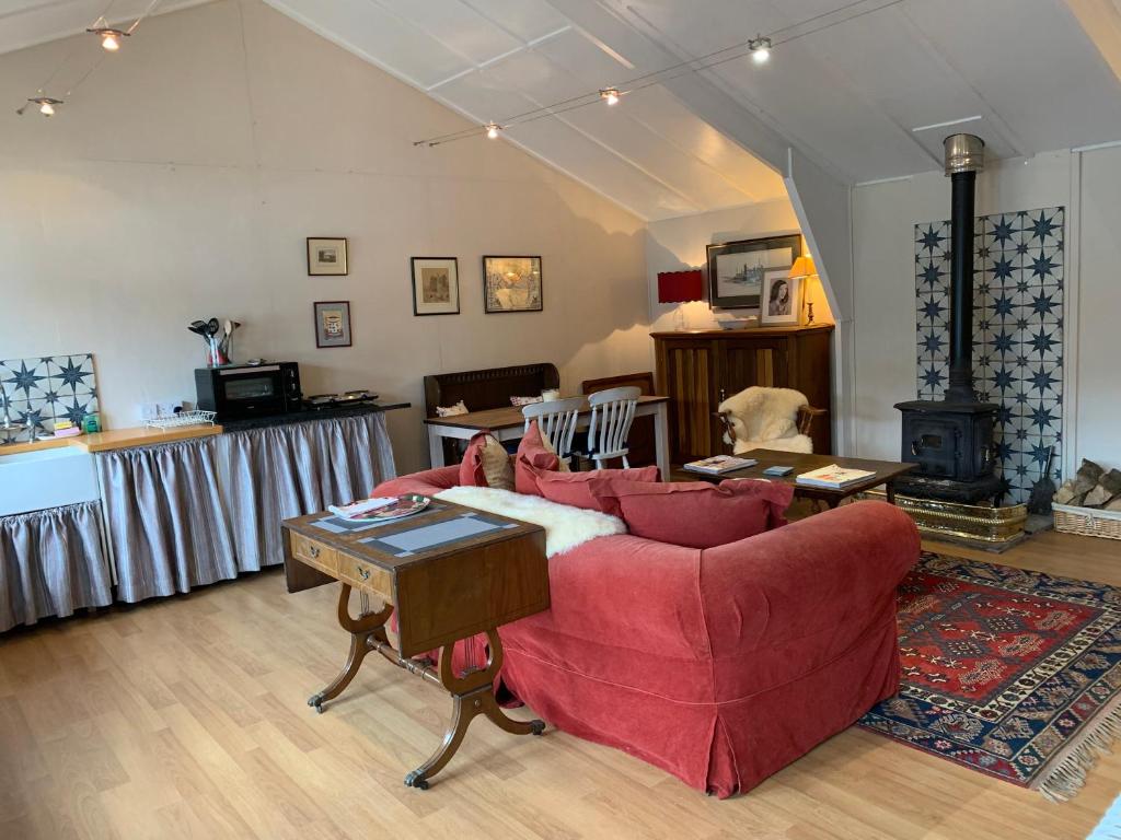 a living room with a red couch and a table at One bedroom lodge in the countryside in Congleton