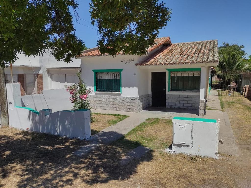 una casa blanca con una puerta y un patio en Casa Vacacional Los Nietos en Quequén