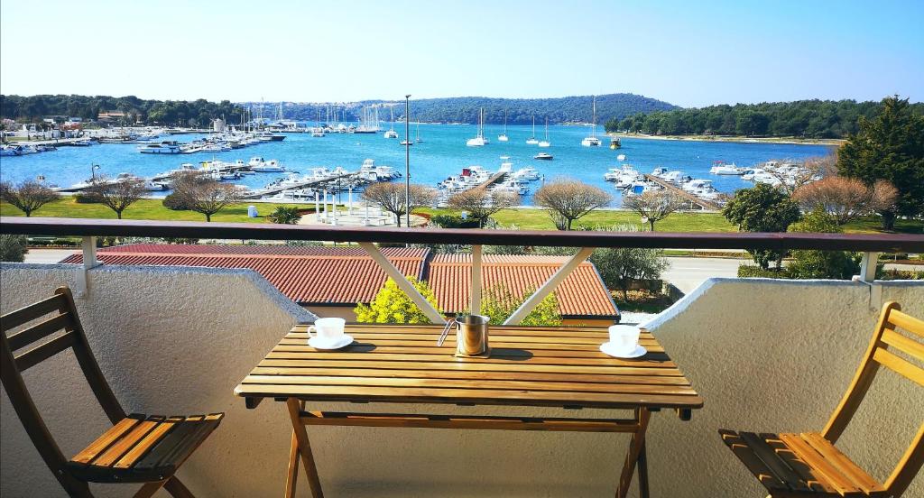 uma mesa de madeira numa varanda com vista para um porto em Dream View Medulin em Medulin