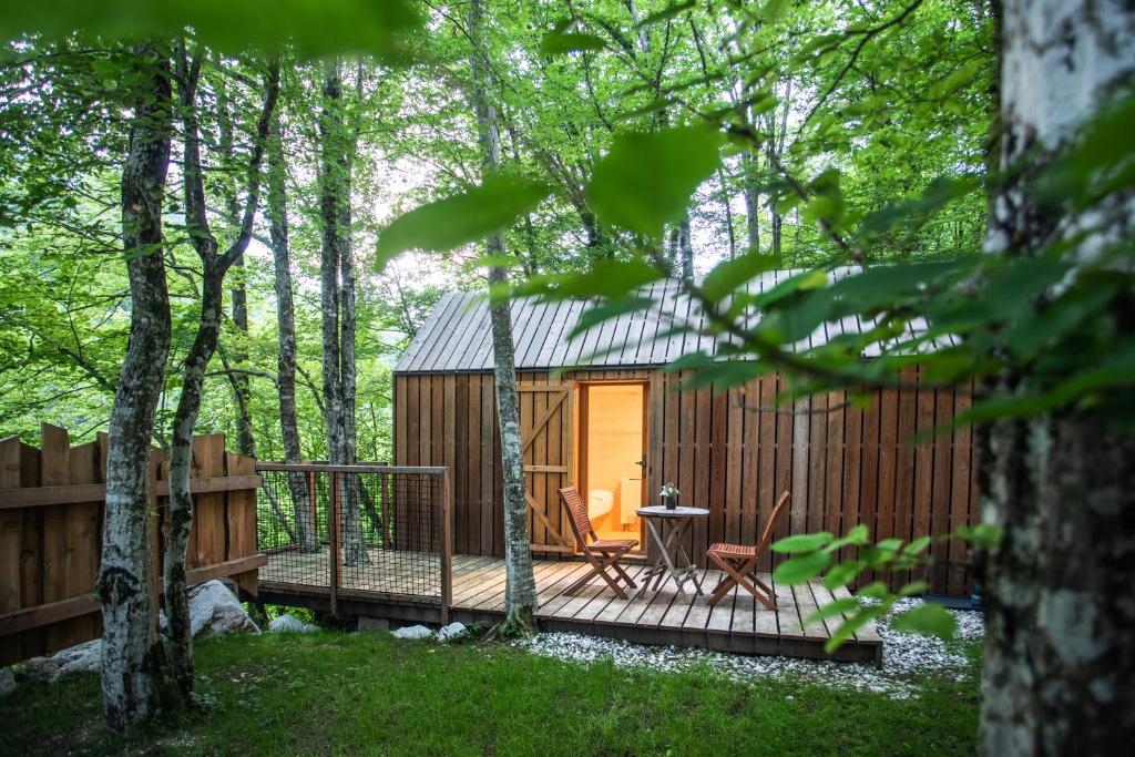 eine Hütte im Wald mit einer Holzterrasse in der Unterkunft Kamp Koren Kobarid in Kobarid