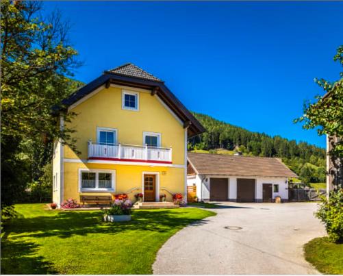 Casa amarilla grande con balcón en un patio en Ferienhaus Reinfrank en Sankt Michael im Lungau