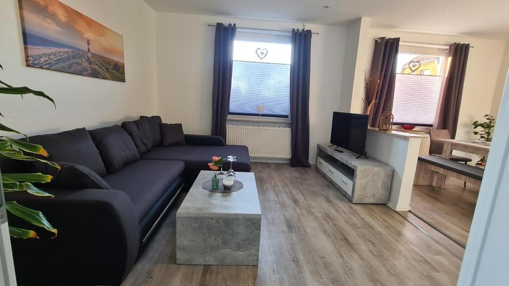 ein Wohnzimmer mit einem schwarzen Sofa und einem TV in der Unterkunft Ferienhaus Femke in Emden