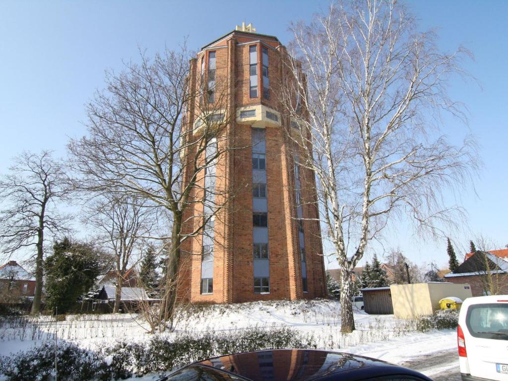 a tall brick building with snow on the ground at Apartment in the water tower, Güstrow in Güstrow