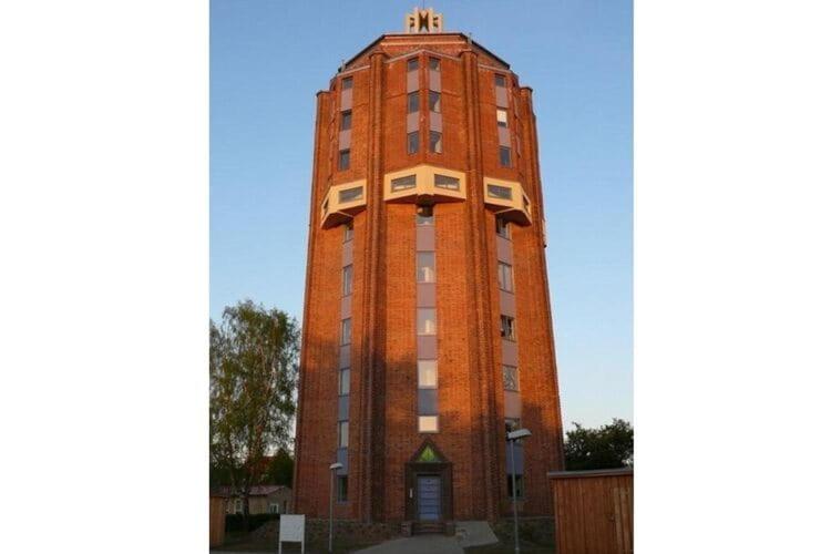 a tall brick building with a clock tower at Holiday flat im Wasserturm Güstrow - DMS01100b-P in Güstrow