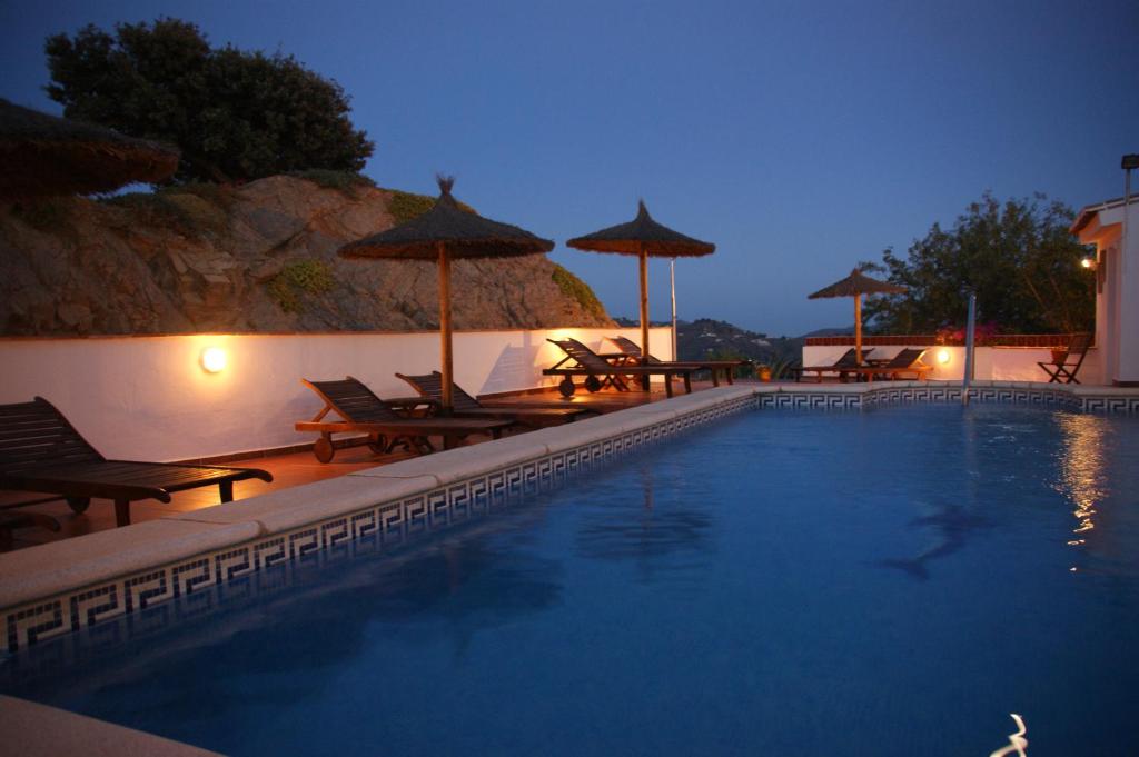 a swimming pool with chairs and umbrellas at night at B&B Casa Agradable in Arenas