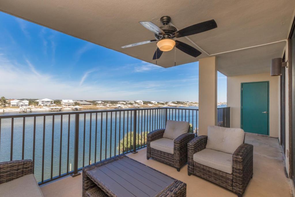 a balcony with two chairs and a ceiling fan at Ole River Hideway, Orange Beach, Updated 2 Bedroom Waterfront Condo, Wind Drift in Orange Beach
