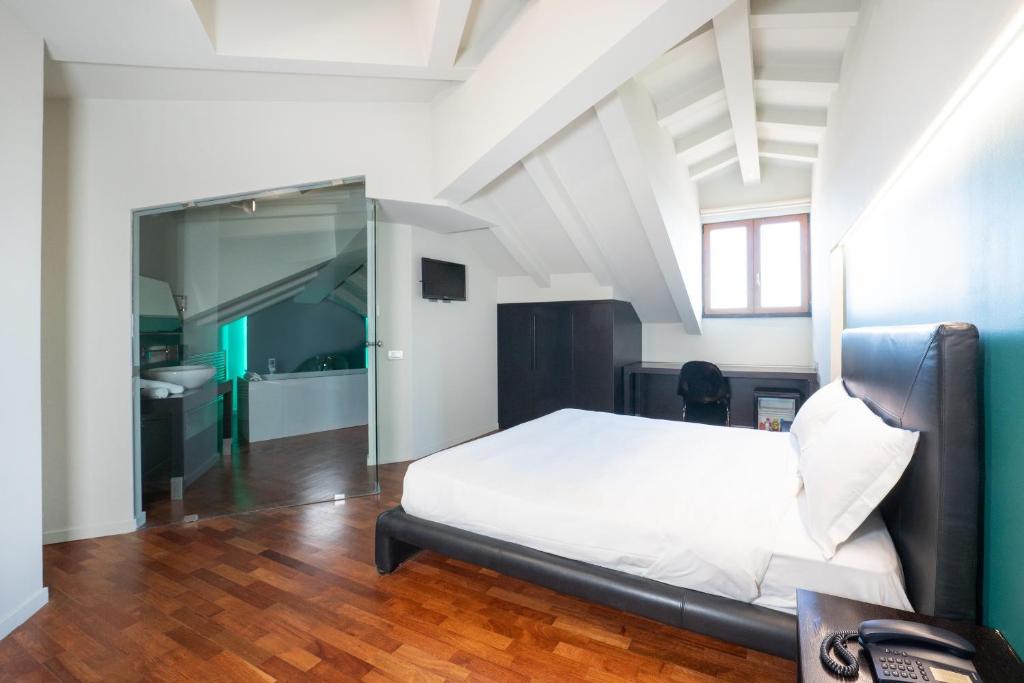 1 dormitorio con cama blanca y baño en SIRIOHotel en Dormelletto