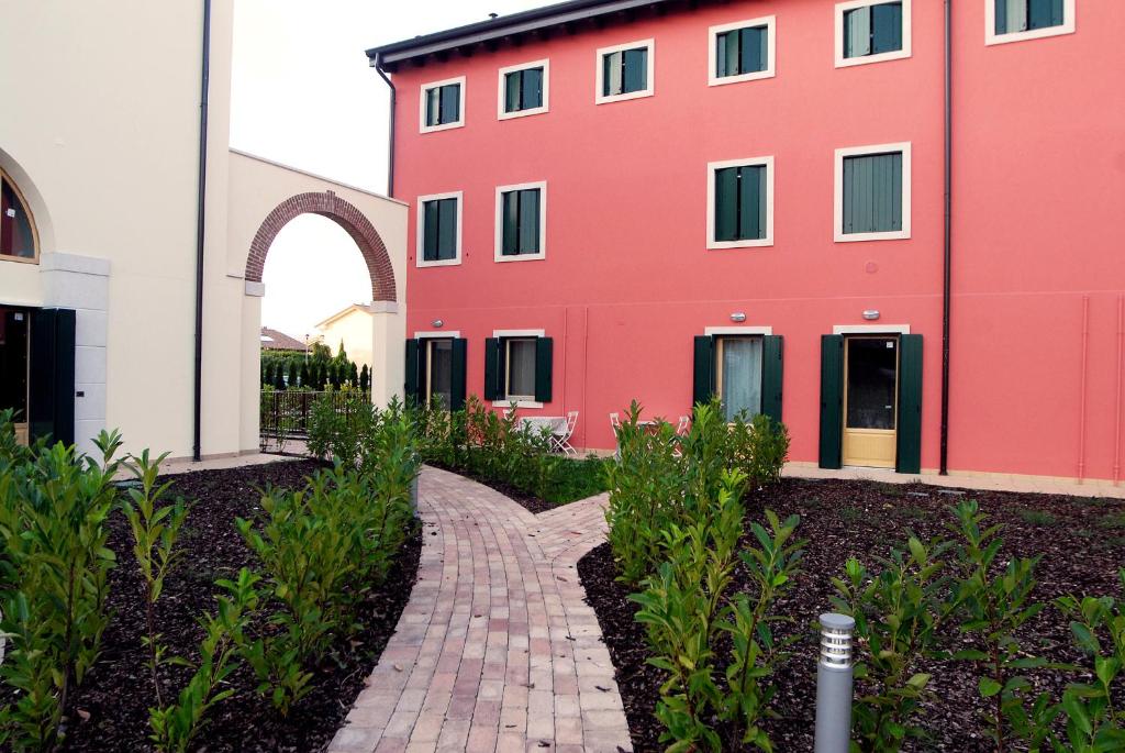 un bâtiment rouge avec une passerelle en briques devant lui dans l'établissement B&B Corte dei Cedri, à Bussolengo