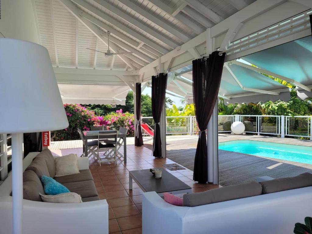 a living room with a couch and a swimming pool at VILLA STE MARTHE avec piscine, grande terrasse, jardin intime et citerne d'eau in Saint-François
