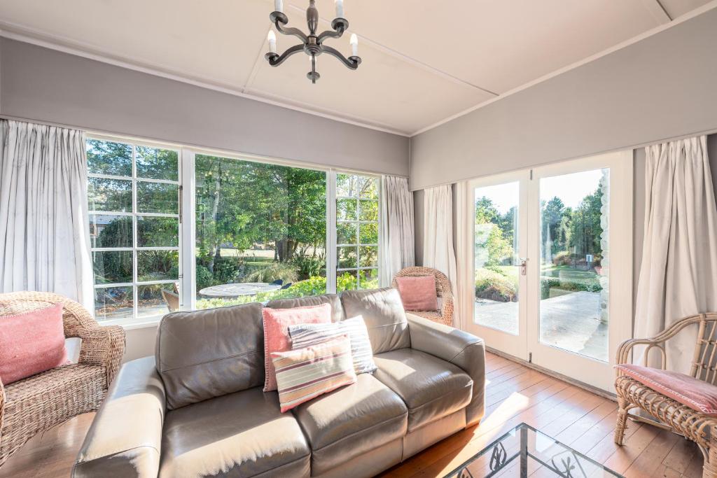 a living room with a leather couch and windows at Mt John Homestead in Lake Tekapo