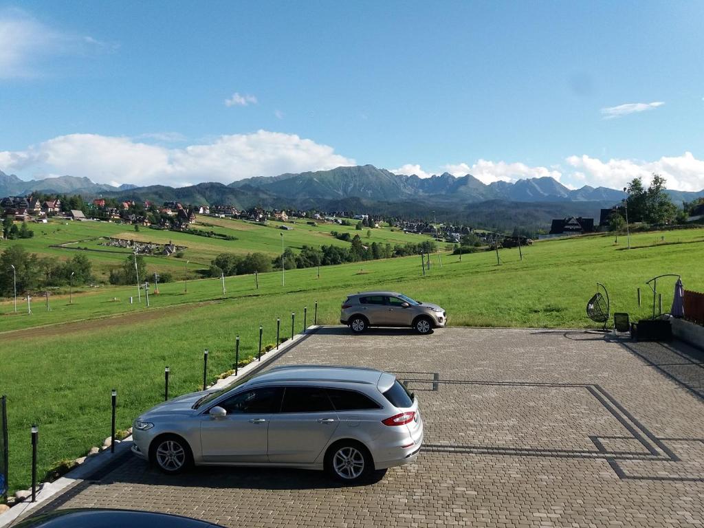 2 voitures garées sur un parking avec des montagnes en arrière-plan dans l'établissement Tatra Widok, à Murzasichle