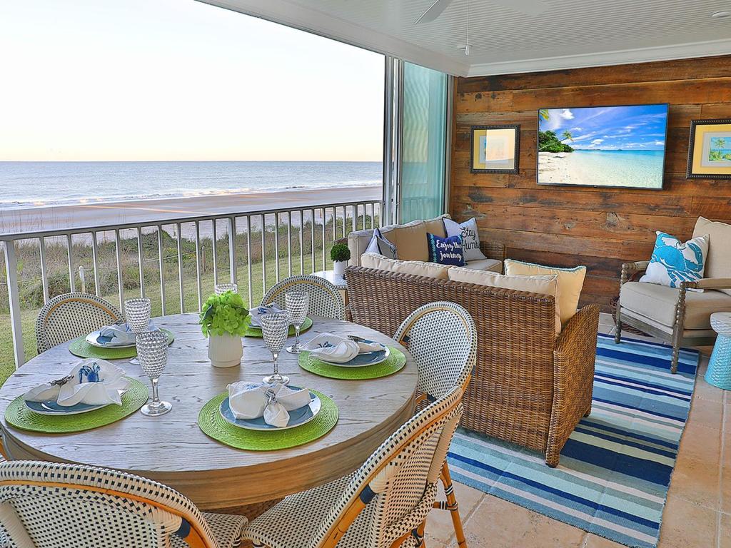 a wooden table with chairs and a couch and the ocean at Ponte Vedra Ocean Manor 106-D, 3 Bedrooms, Beachfront, Sleeps 10 in Ponte Vedra