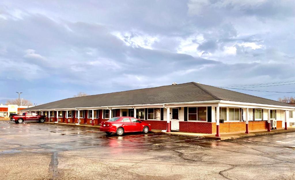 een rode auto geparkeerd voor een gebouw bij The Madison Inn Motel in Fort Madison