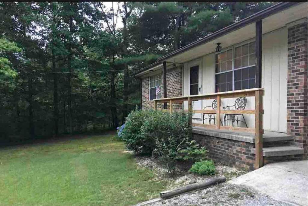 ein Backsteinhaus mit einer Veranda mit einer Bank darauf in der Unterkunft Maggie’s lil Cottage in Sampson