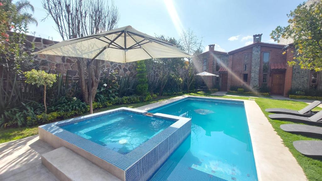 una piscina con sombrilla junto a una casa en Cabañas Doña Anita, en San Miguel Regla