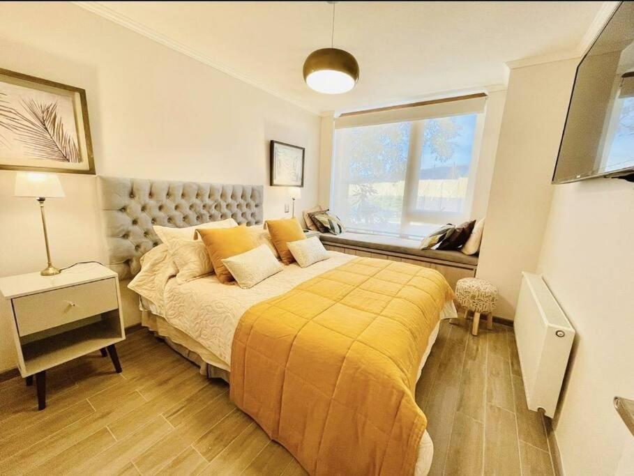 1 dormitorio con 1 cama con edredón amarillo y ventana en Departamento Nuevo Pucón, en Pucón
