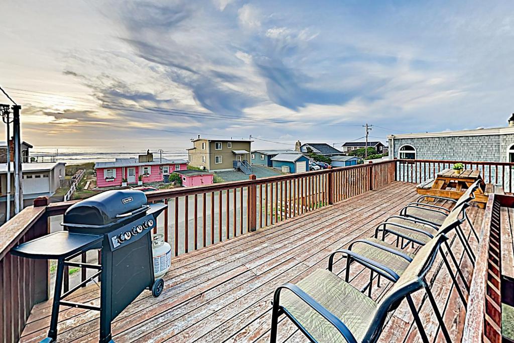 a deck with two chairs and a grill on it at Pelican Harbor in Rockaway Beach