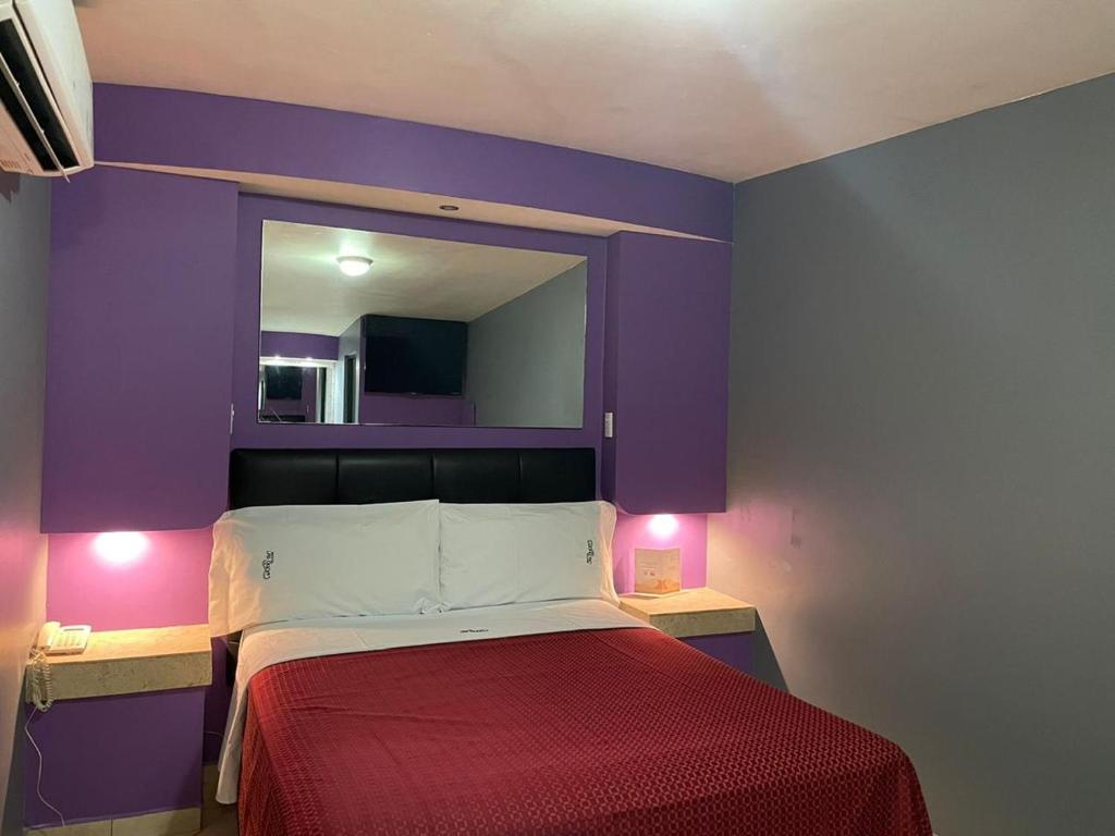 a bedroom with purple walls and a bed with a red blanket at Motel Las Dunas in Mexicali