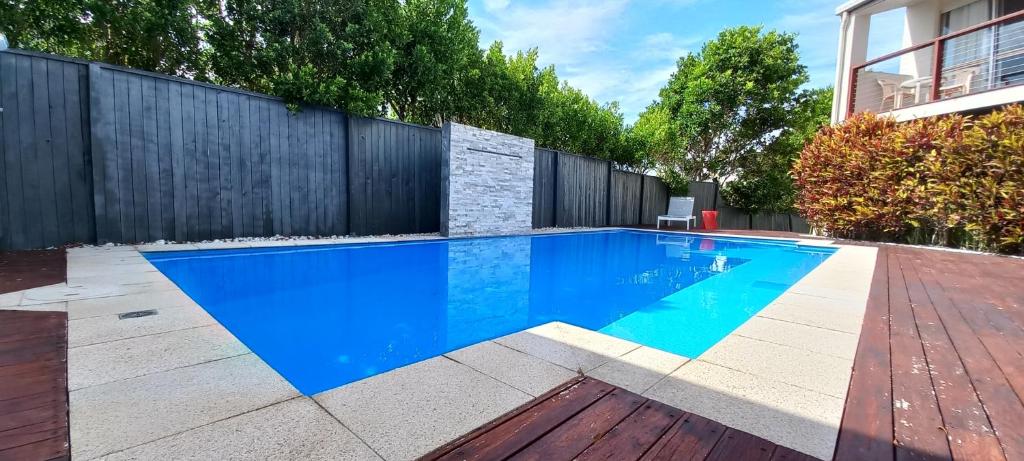 una piscina en un patio trasero con una valla de madera en Ocean Sounds, en Peregian Beach