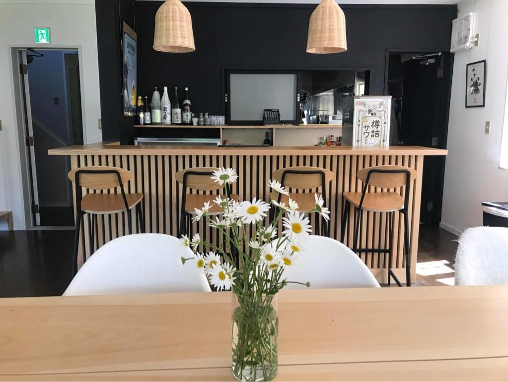 un tavolo con sedie bianche e un vaso di fiori di Myoko Forest Lodge a Myoko