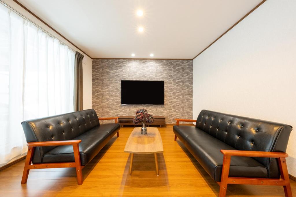un soggiorno con 2 divani in pelle e una TV di neige furano Vacation rented house a Furano