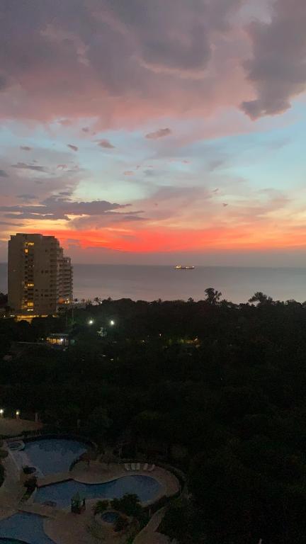 um pôr-do-sol sobre a água com uma cidade e edifícios em Apartamento Santa Marta - Zazue - Bello Horizonte em Santa Marta