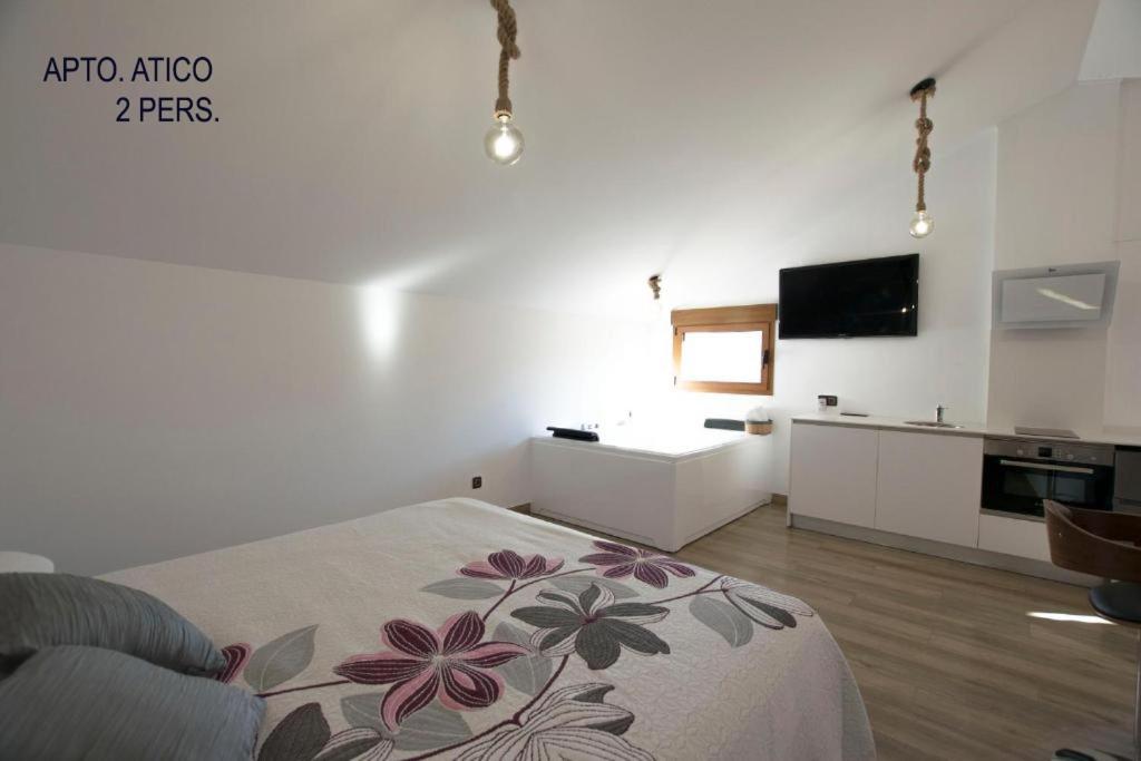 a white room with a bed and a kitchen at El Tranco Apartamentos in Villel