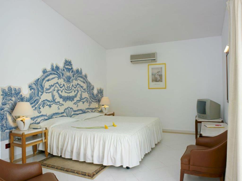 a blue and white bedroom with a bed and two chairs at Hotel Apartamento Do Golfe in Vilamoura