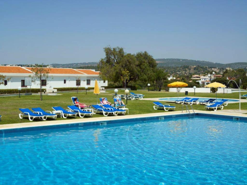 a large swimming pool with chairs and umbrellas at Hotel Apartamento Do Golfe in Vilamoura