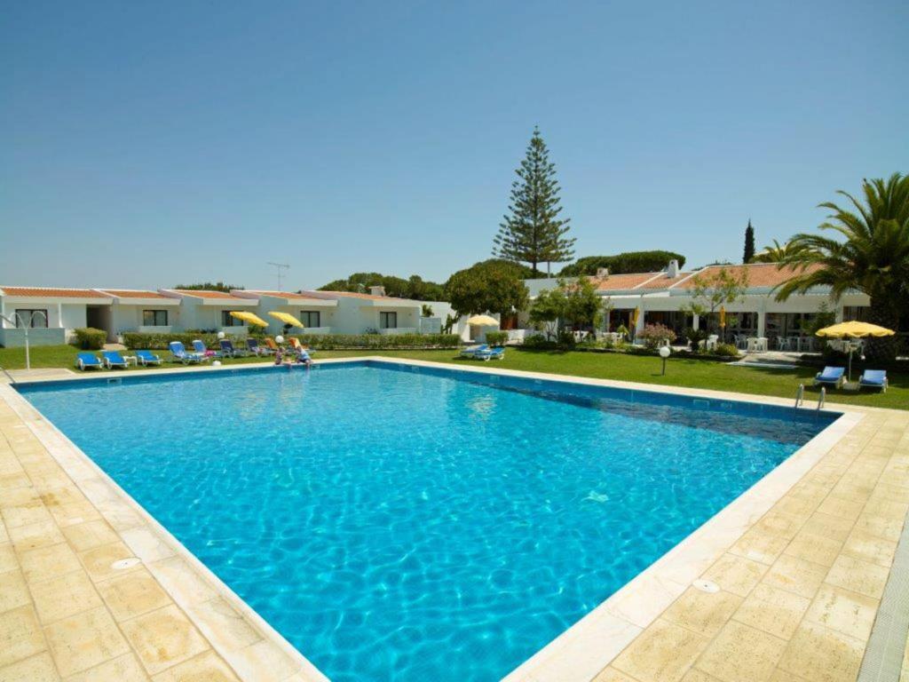 a large blue swimming pool in front of a house at Hotel Apartamento Do Golfe in Vilamoura