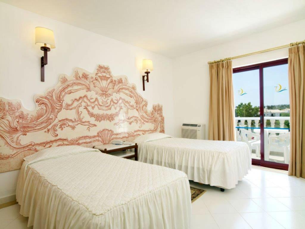 a hotel room with two beds and a window at Hotel Apartamento Do Golfe in Vilamoura