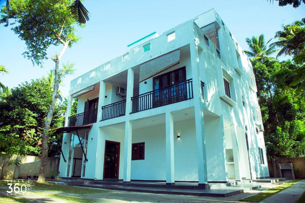 a white building with a balcony on it at Villa 360 in Talpe
