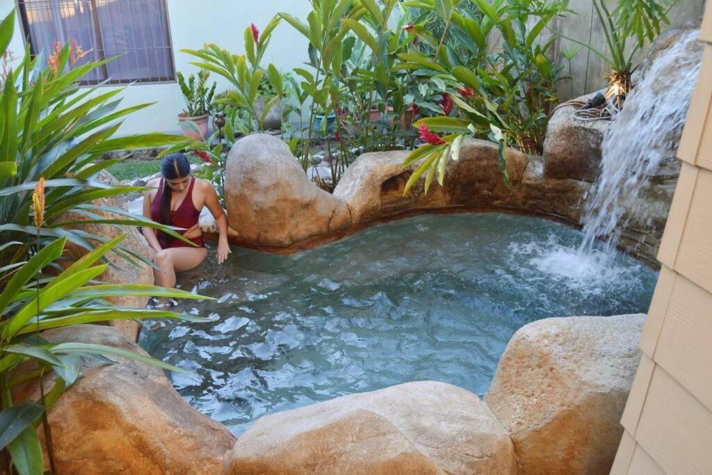 una mujer sentada junto a una cascada en un jardín en Elegant Villa in La Fortuna with spacious backyard plus very private pool & parking en Fortuna