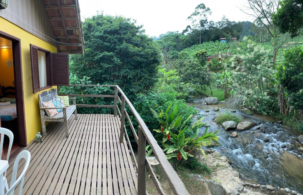 a wooden walkway leading to a river next to a house at Casa em Lumiar - Barulhinho do Rio in Lumiar