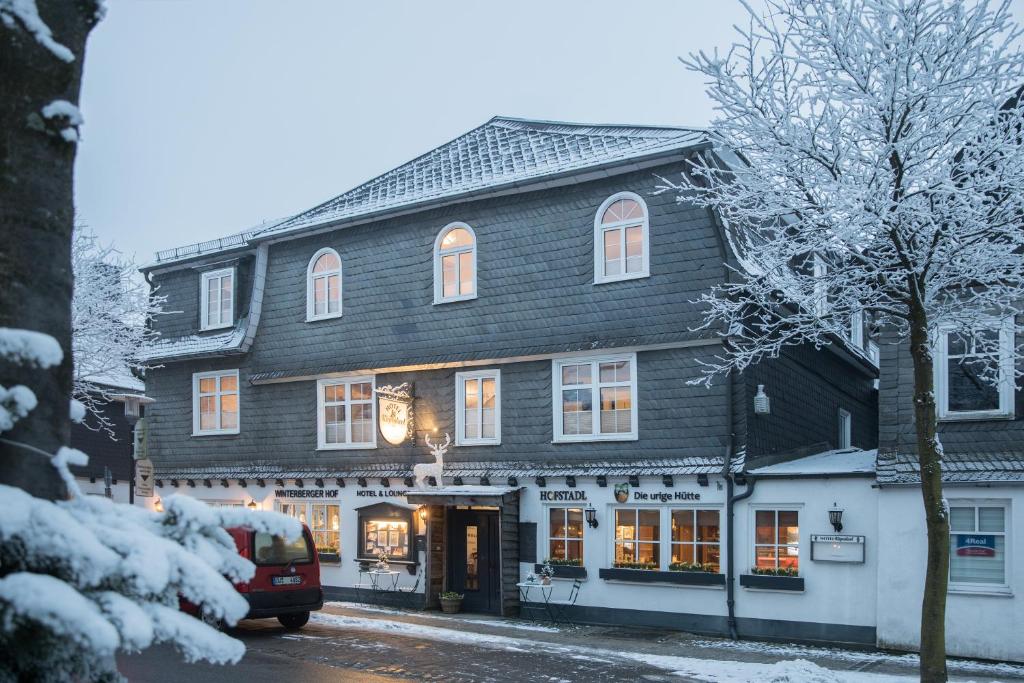 ein großes Holzgebäude mit einem Geschäft in einer verschneiten Straße in der Unterkunft Hotel Kiepenkerl in Winterberg