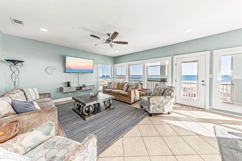 a living room with a couch and chairs and a tv at Grotto on the Gulf in Fort Morgan