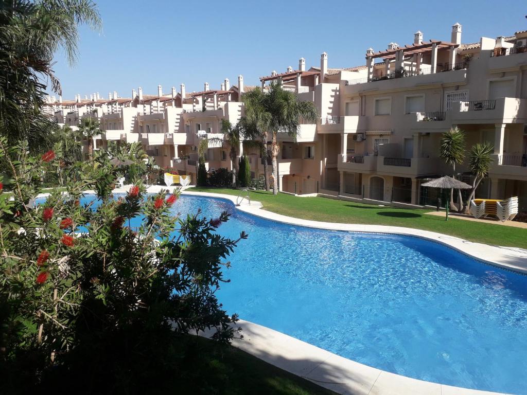 a large swimming pool in front of a building at Duquesa Fairways, a spacious apartment with fabulous views and facilities in Manilva