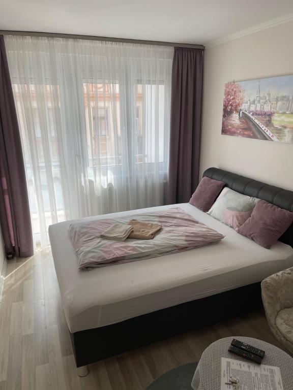 łóżko w pokoju z dużym oknem w obiekcie Classic City Apartman w Segedynie