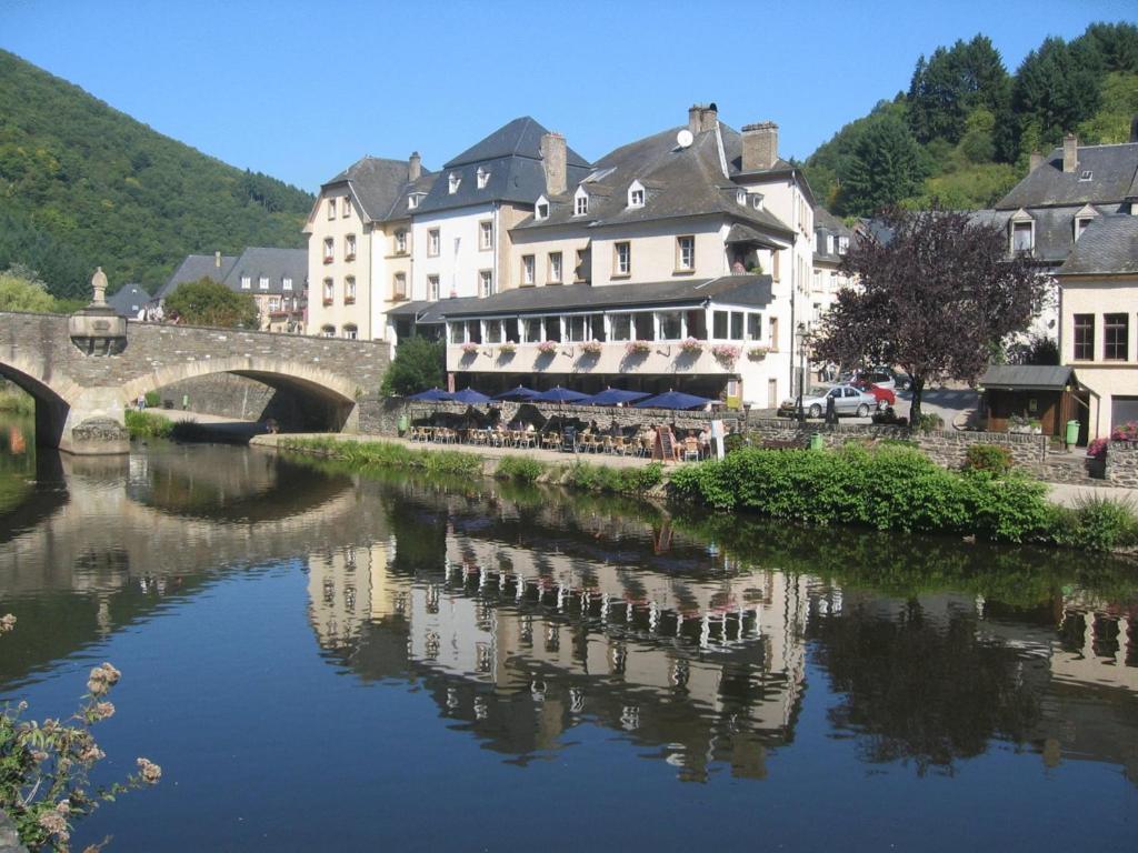 a river in a town with a bridge and buildings at Auberge de Vianden in Vianden