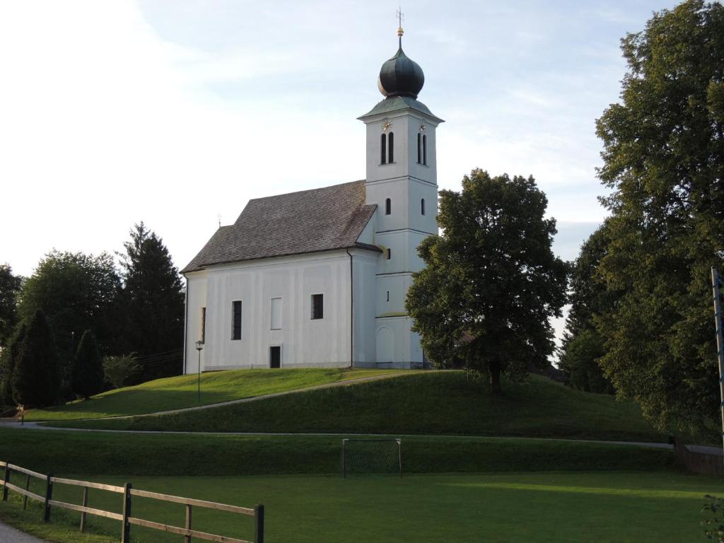 a white church with a steeple on top of a hill at Familienglück in der Weststeiermark in Sankt Oswald ob Eibiswald