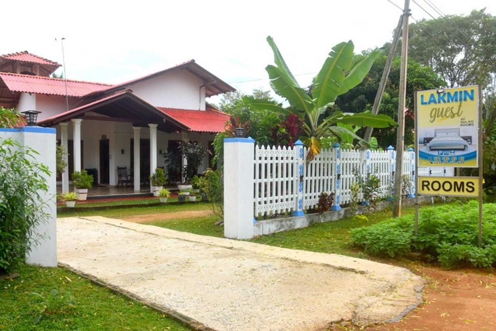 a house with a white fence and a sign at Wilpattu Lakwin Guest in Pahala Maragahawewa