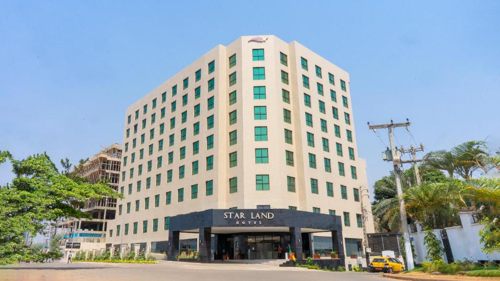 Un grand bâtiment blanc avec un panneau devant. dans l'établissement STAR LAND HOTEL BASTOS, à Yaoundé