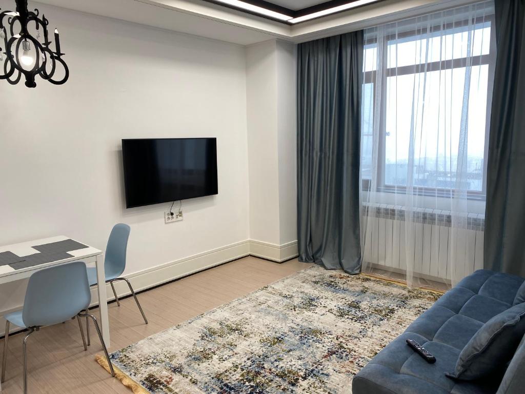 sala de estar con sofá, mesa y TV en ЖК Highvill Ishim D1 en Astaná