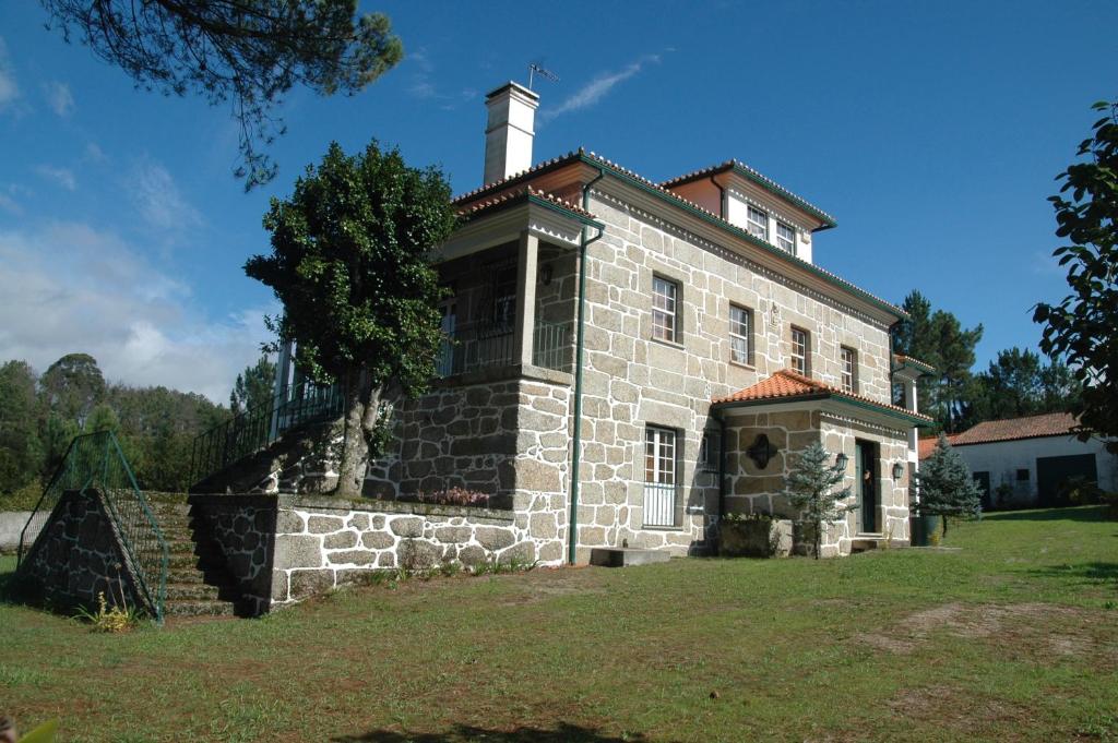 una antigua casa de piedra con chimenea en la parte superior en Casa das Eiras, en Tondela