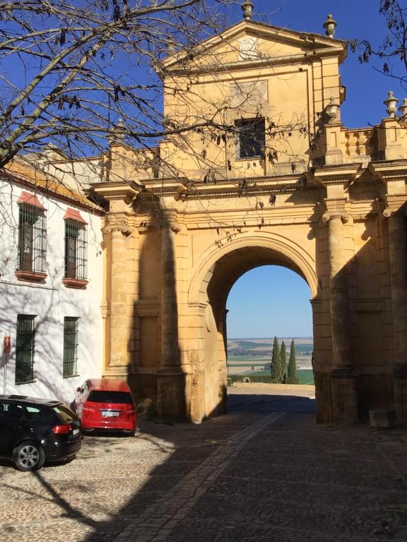 un arco en un edificio con un coche rojo estacionado en Puerta Romana, en Carmona