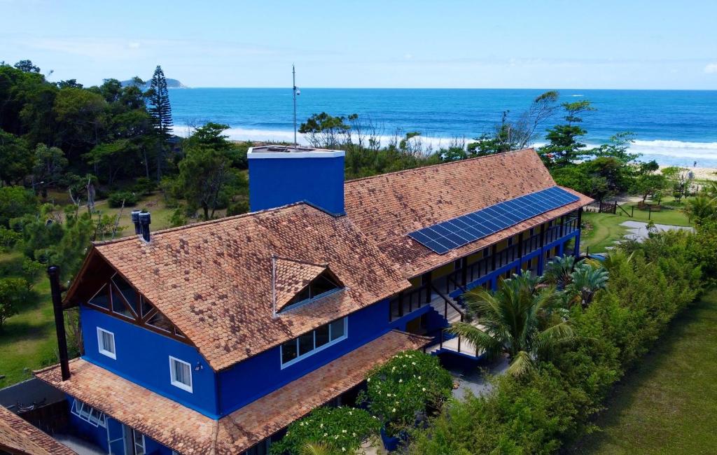 una vista aérea de una casa azul con el océano en el fondo en Pousada Penareia Floripa, en Florianópolis