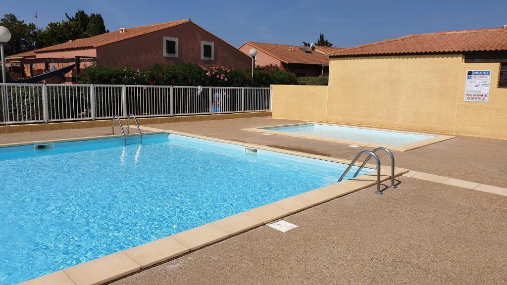une grande piscine bleue à côté d'un immeuble dans l'établissement Charmant pavillon proche plage - Piscine & parking, à Narbonne-Plage