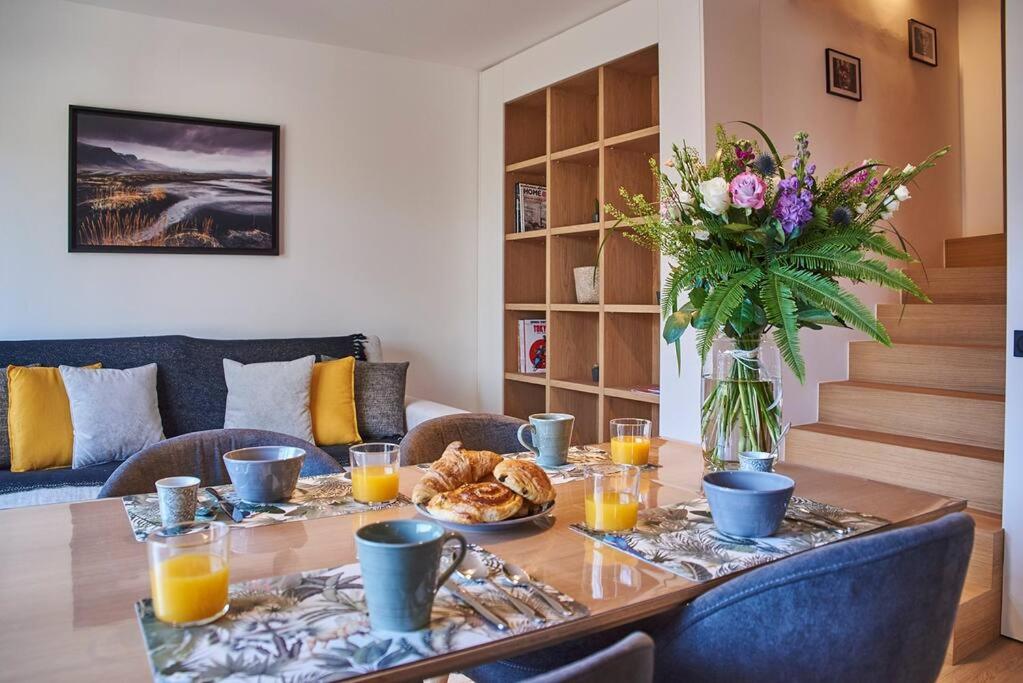 einen Esstisch mit einer Vase aus Blumen und Essen in der Unterkunft Magnifique Appartement Design Parking Chiberta in Anglet