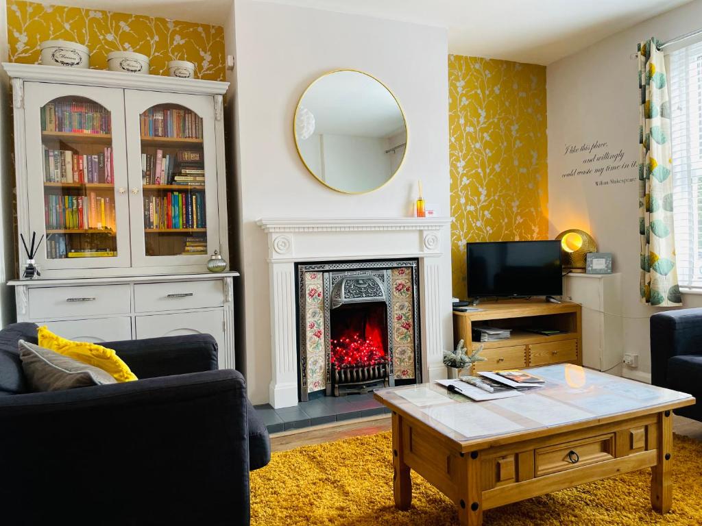 a living room with a fireplace and a table at Arden Holiday Lettings in Stratford-upon-Avon